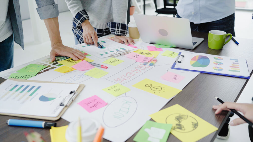 Groupe d'hommes d'affaires en tenue décontractée discutant d'idées au bureau. Des professionnels de la création sont réunis autour d'une table de réunion pour discuter des questions importantes liées à un nouveau projet de création d'entreprise couronné de succès.